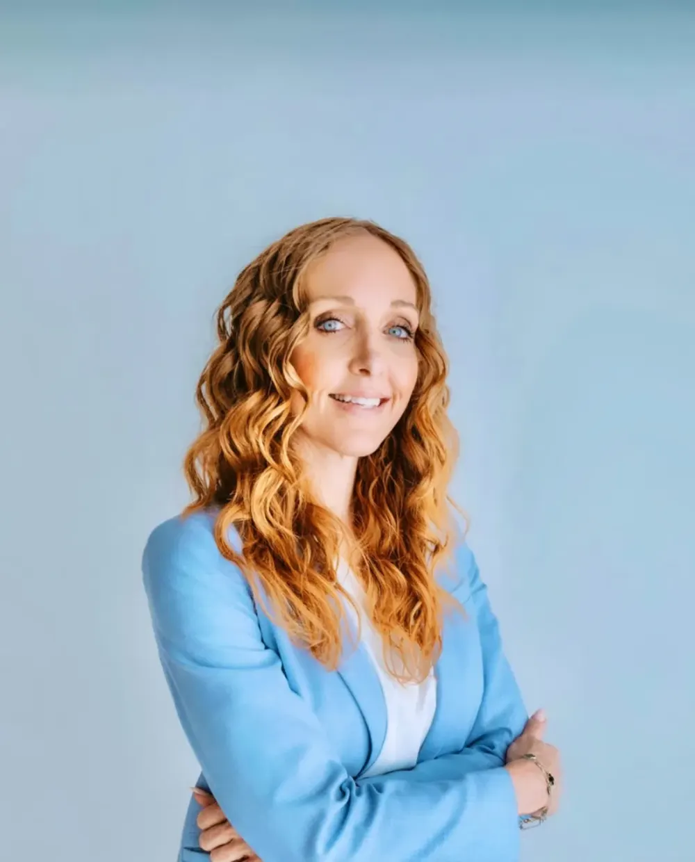 Shannon “Redd”, arms crossed, in a light blue blazer